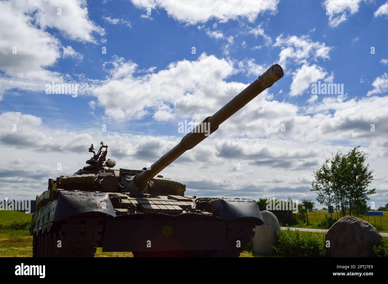 A large green military metal armored deadly dangerous iron Russian Syrian battle tank with a gun turret and a goose is parked parked against a blue sk Stock Photo