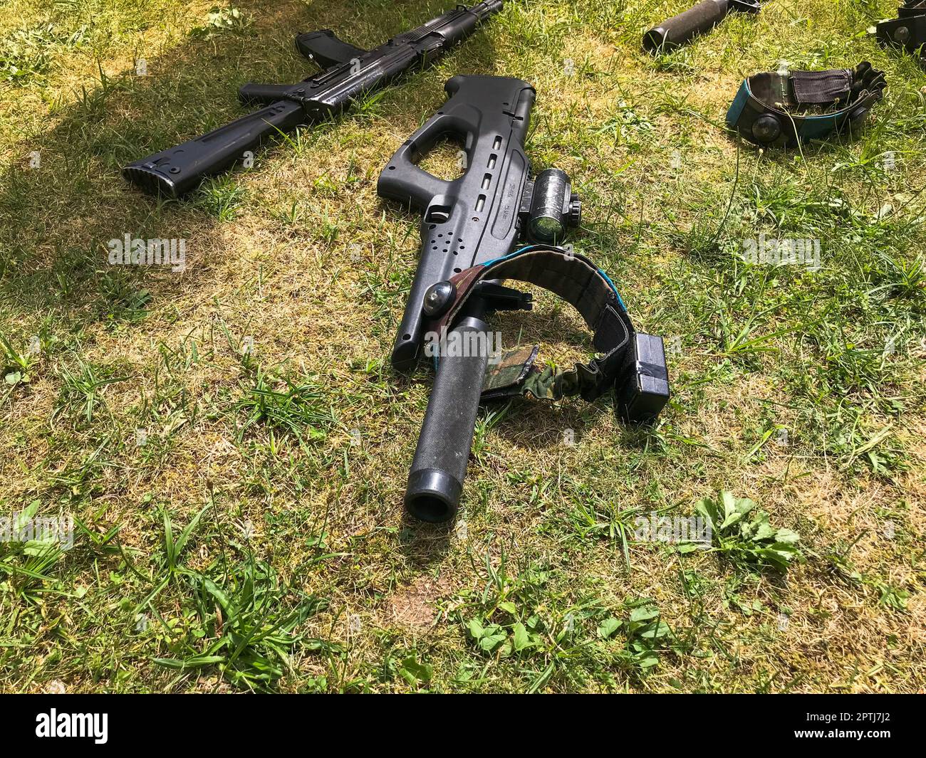 Black iron metal army military machine guns, small arms for soldiers with silencers lie on the background of green grass. Stock Photo