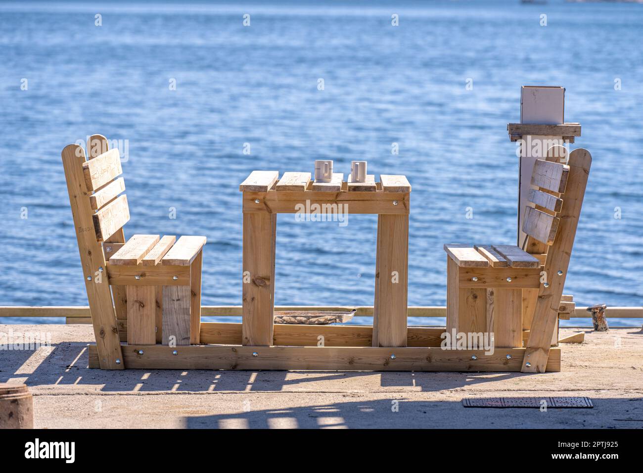 Two mugs on a table by benches by the sea Stock Photo