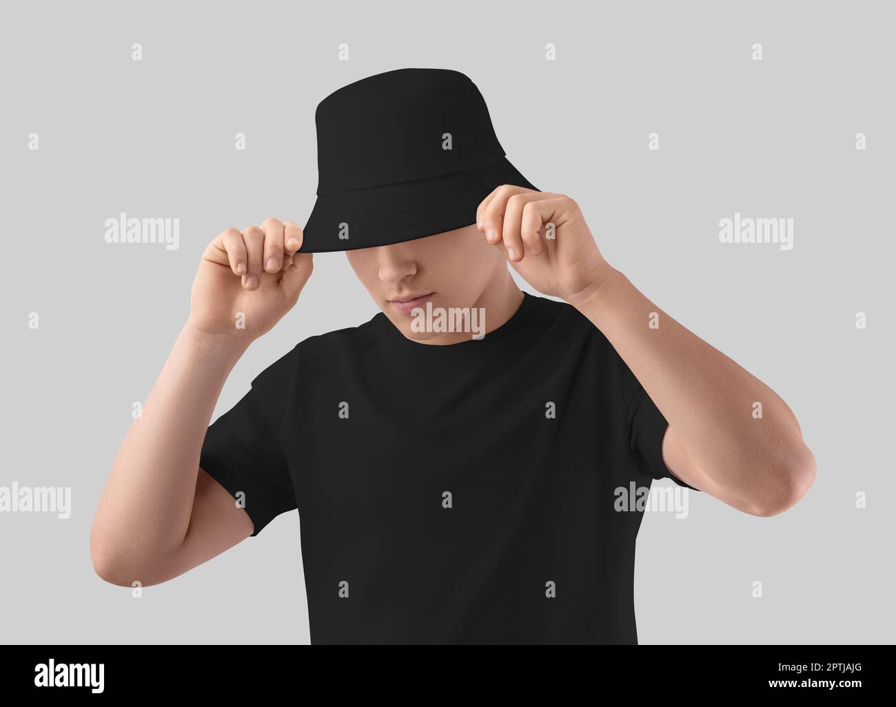 Mockup of a black hat on a young guy in a t-shirt, holds a universal accessory for design, brand. Stylish summer headwear template, product photograph Stock Photo