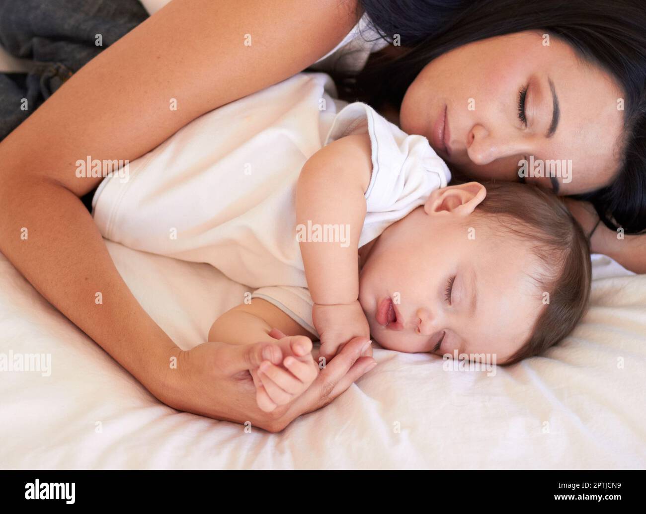 Baby, sleeping and mother holding hands on bed with parent support, care and love. Relax, home