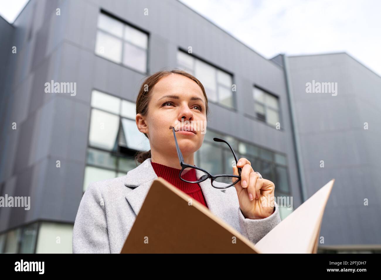 Portrait of young businesswoman with glasses holding folder with documentation in her hands. Stock Photo