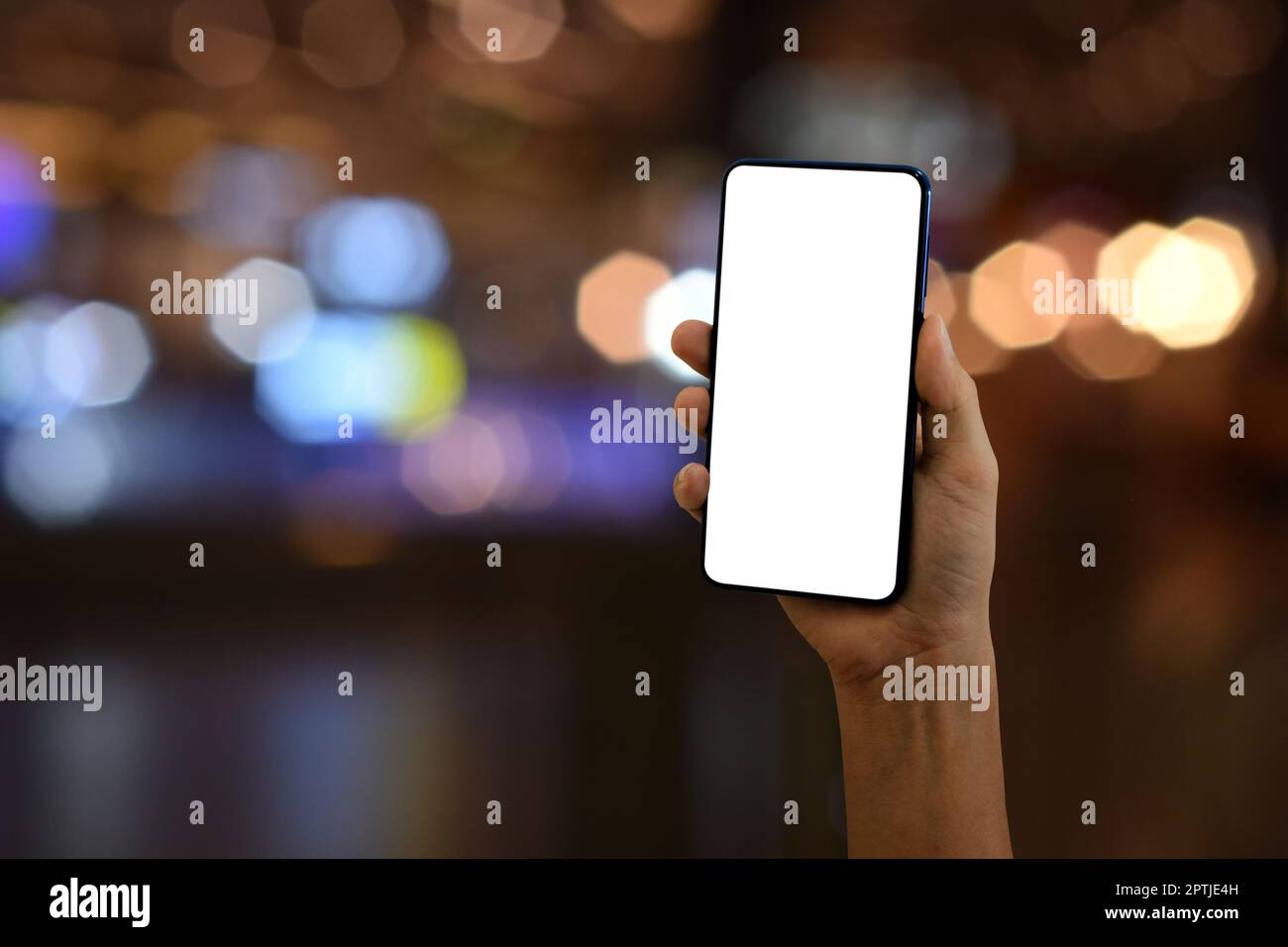 Hand holding smartphone with blank screen on bokeh light background ...
