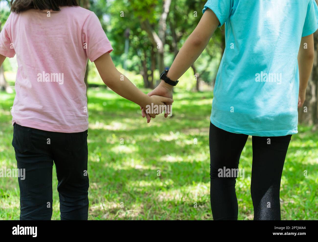 Two sister holding hands in the park in warm spring day. Happy friendship family concept. Stock Photo