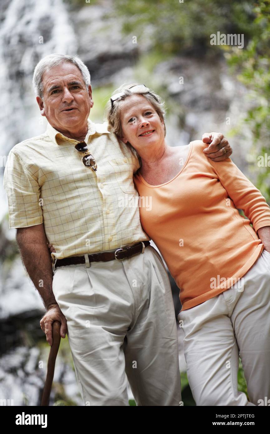 A leisurely stroll through the forest. Portrait of a senior couple standing before a picturesque waterfall Stock Photo