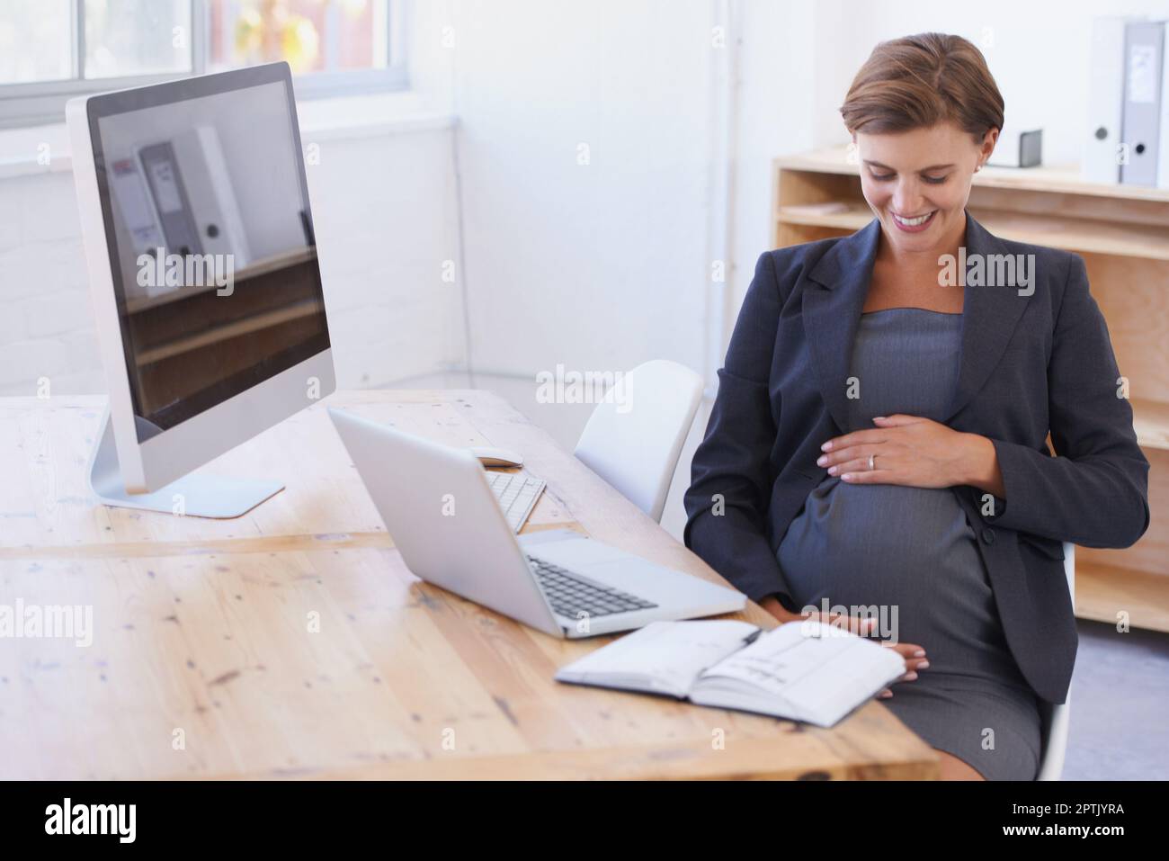 I cannot wait to meet you. A pregnant businesswoman smiling