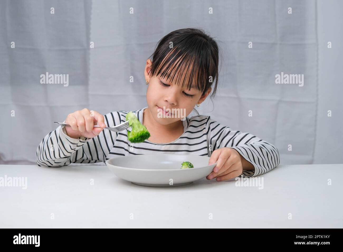 Children love to eat vegetables. Cute Asian girl eating healthy