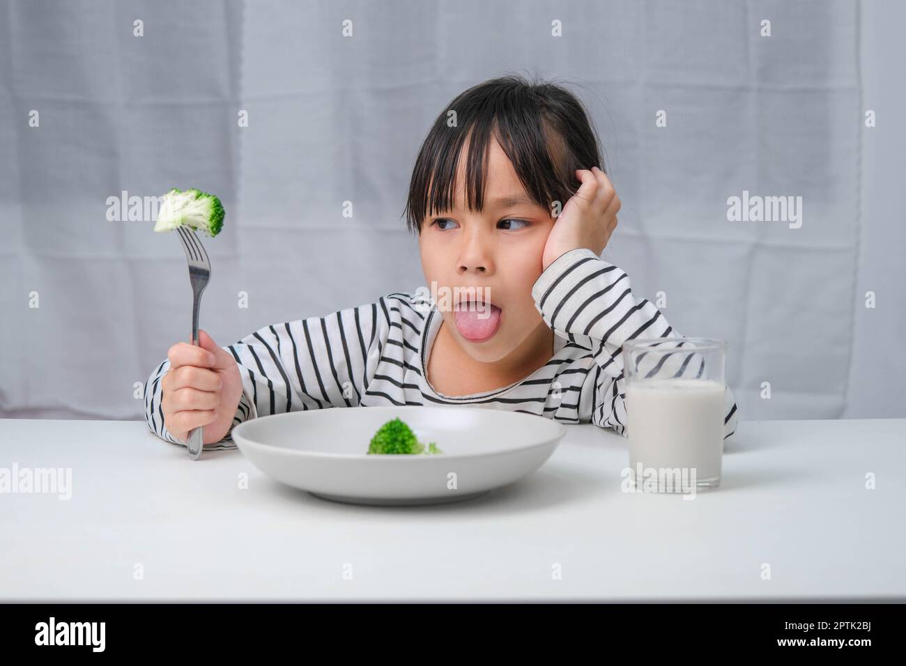 Children don't like to eat vegetables. Cute Asian girl refusing to eat healthy vegetables