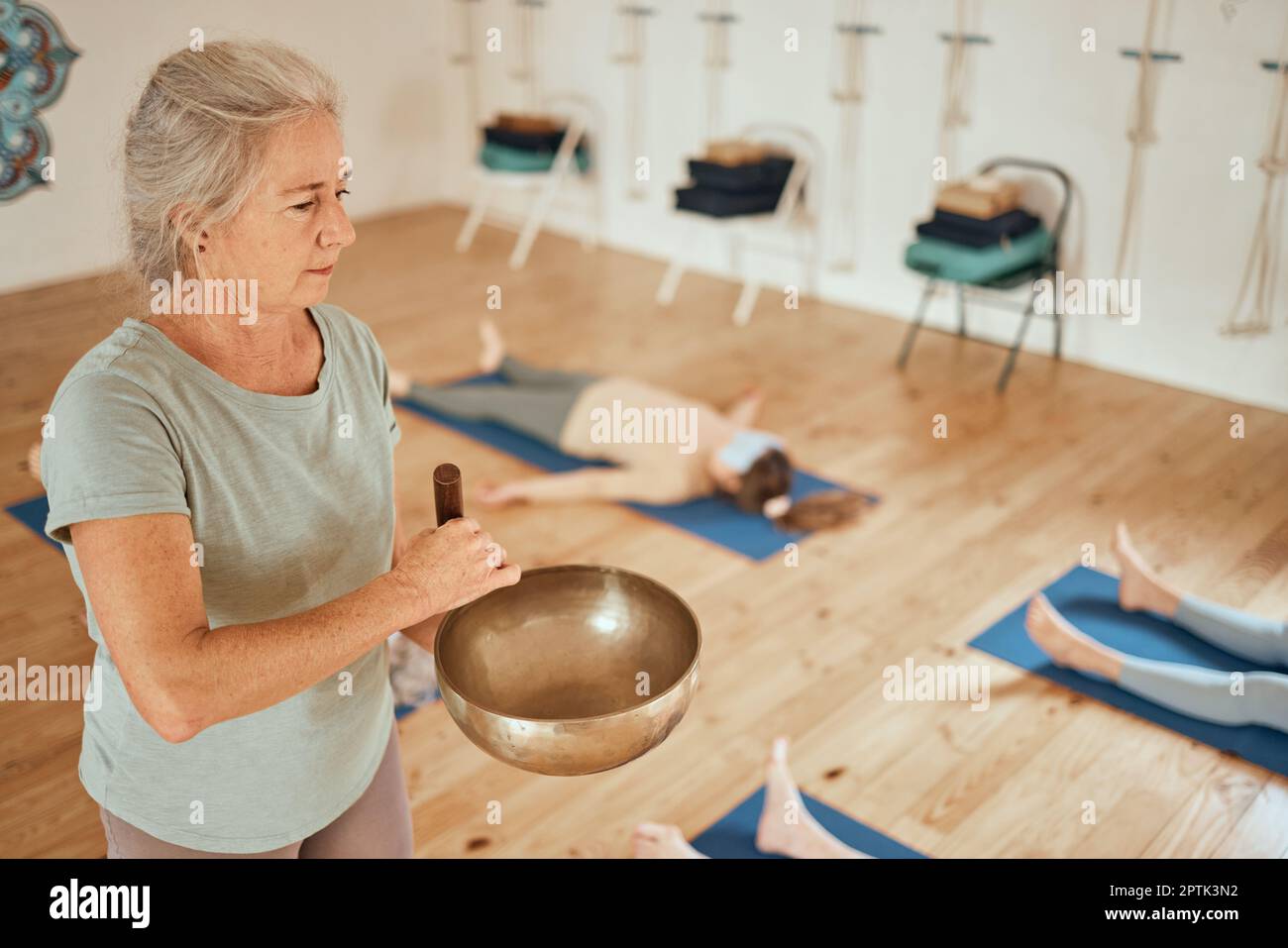 Meditation, class and woman with Tibetan singing bowl for calm, peace and zen in gym studio. Spiritual healing, mindfulness and senior fitness coach i Stock Photo