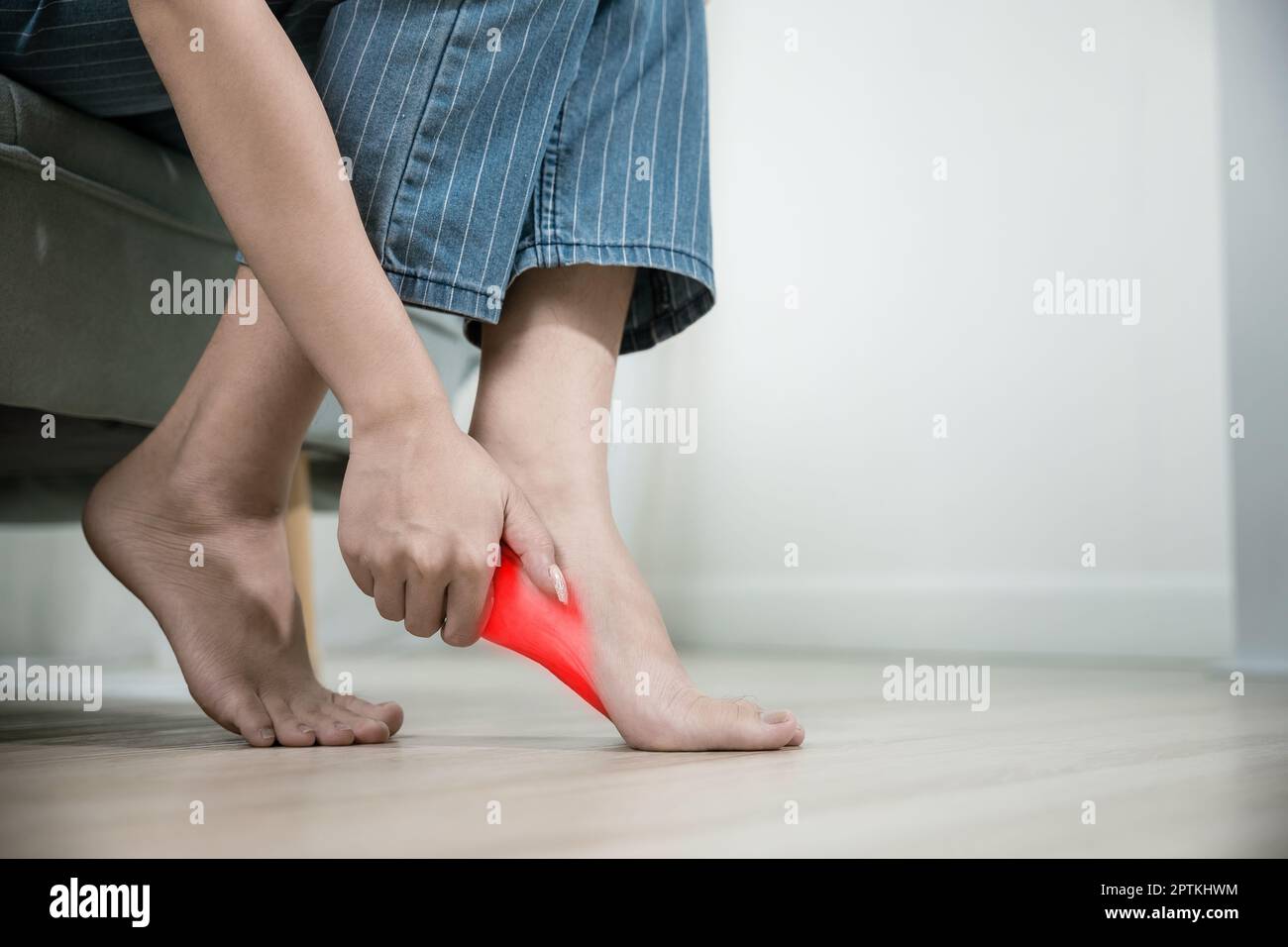 Asian beautiful female problems with foot at home, painful ankle injury,  Young woman sitting on sofa holding her feet and stretch muscles have  symptom Stock Photo - Alamy