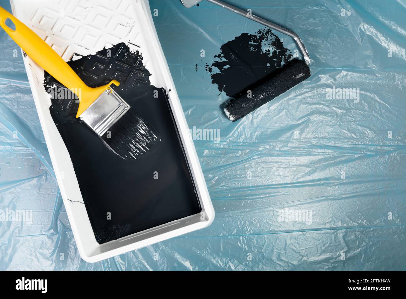 Paint brush and roller with white bucket on a blue wrinkled plastick ...