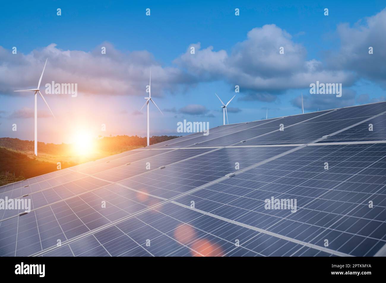 Solar panels with wind turbines against blue sky background ...
