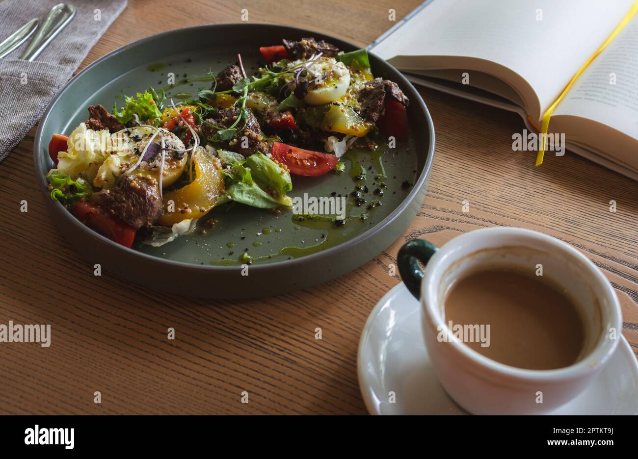 Serving salad with coffee cup and open book. Book with bookmark and