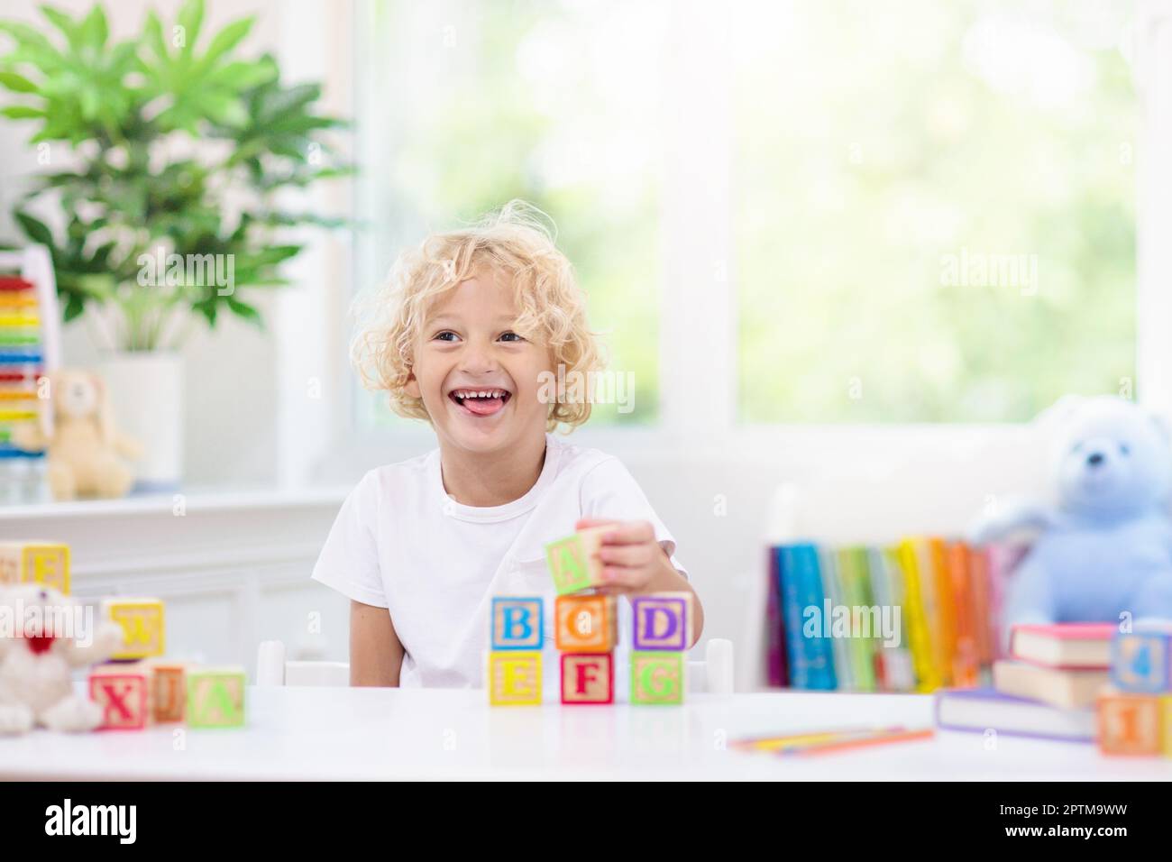 Child learning letters and numbers. Kid with colorful wooden abc blocks