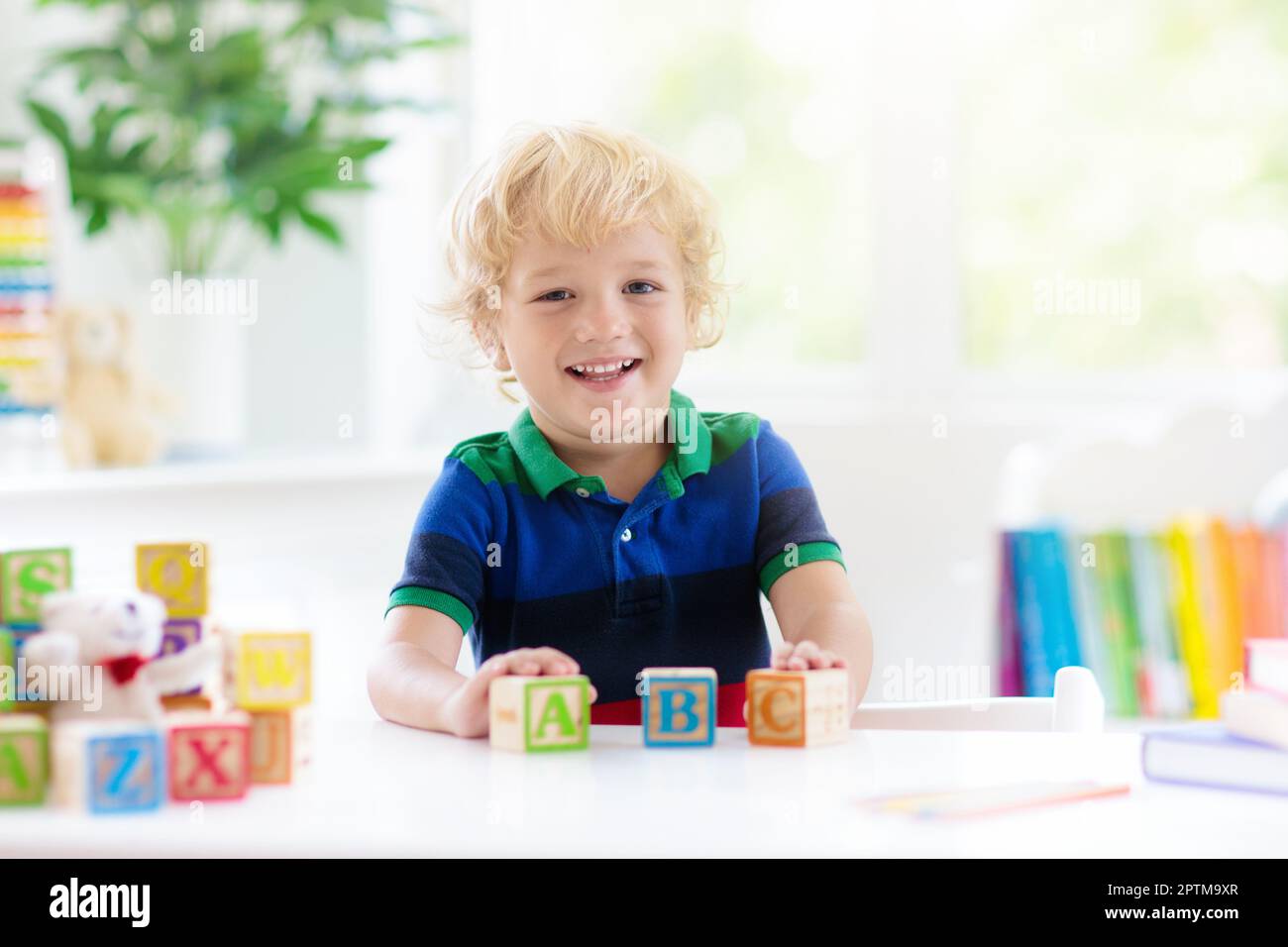 Child learning letters and numbers. Kid with colorful wooden abc blocks