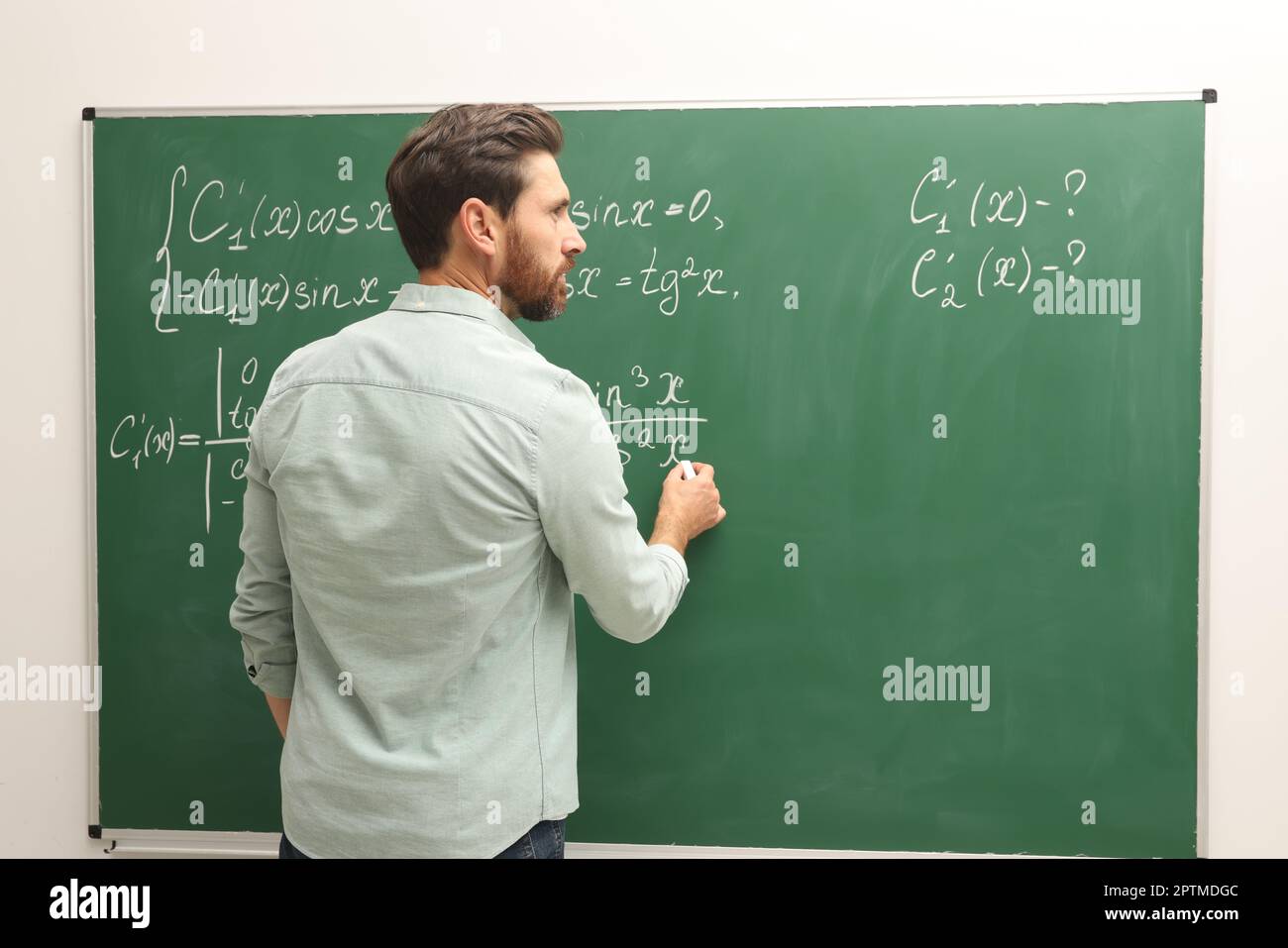 Mature teacher explaining mathematics at chalkboard in classroom Stock ...