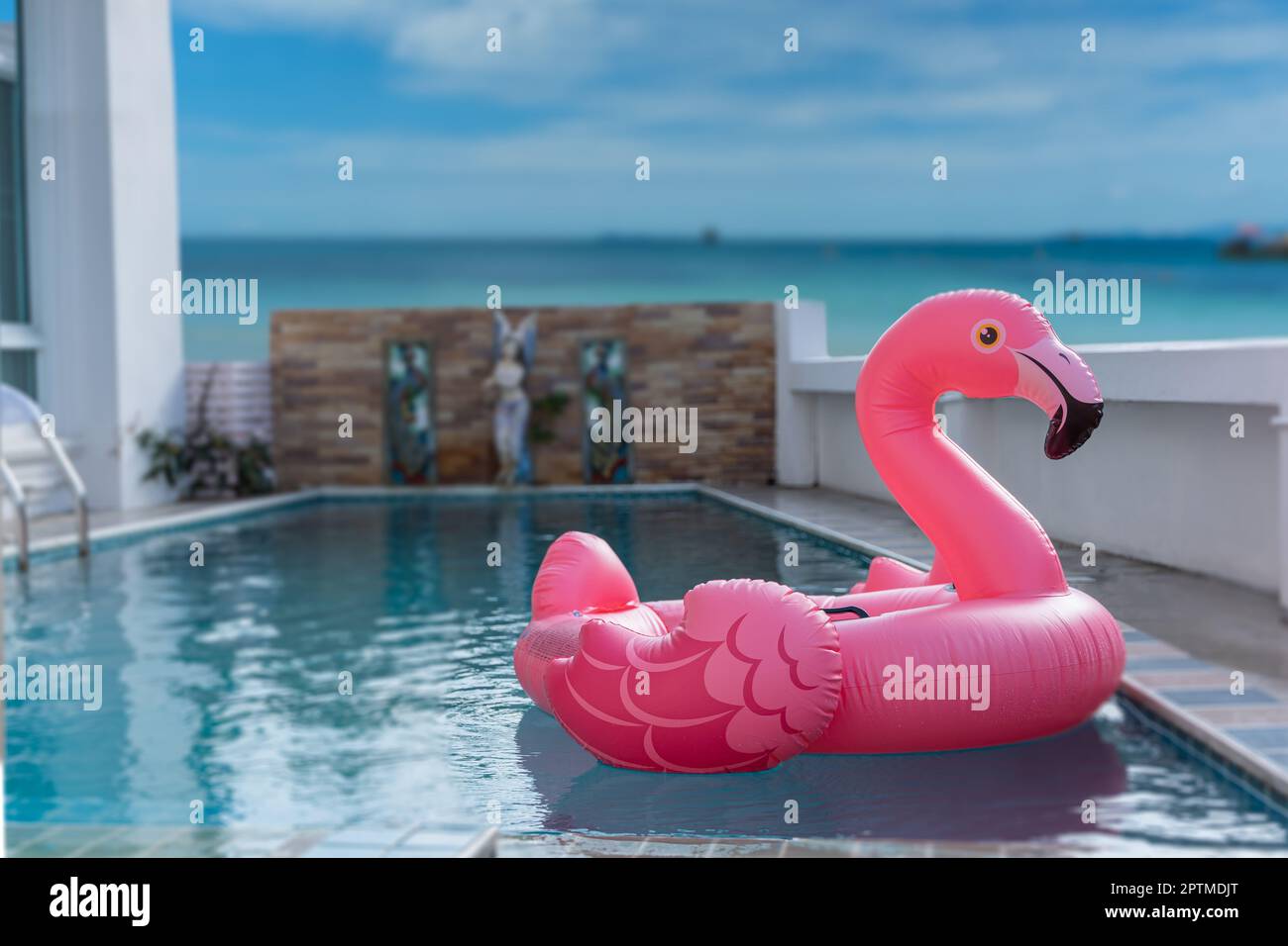 Pink inflatable flamingo on swimming pool. Concept for summer day Stock Photo