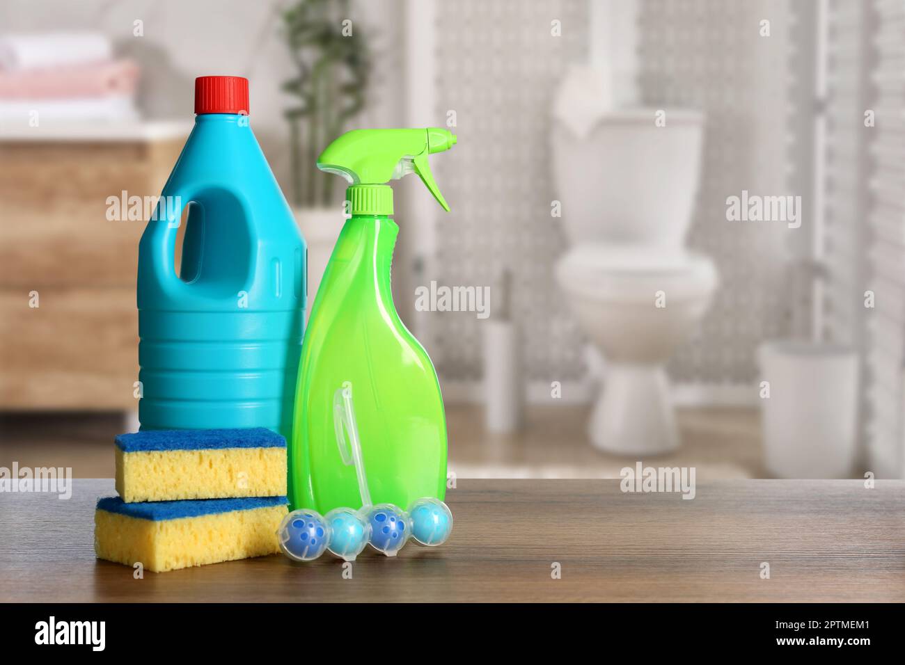 Different toilet cleaning supplies on wooden table in bathroom