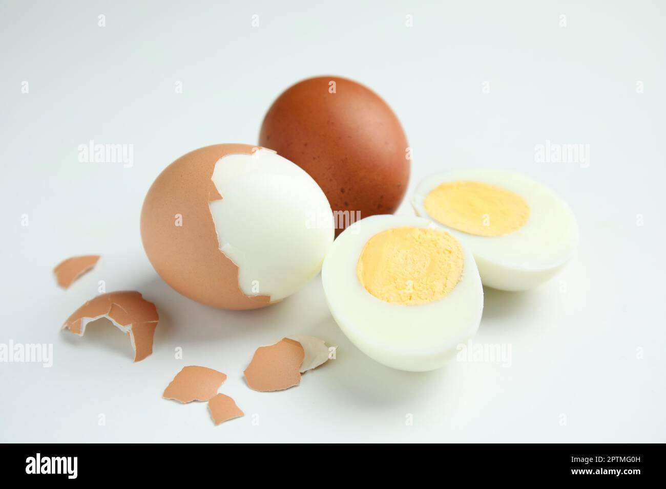 Hard boiled eggs and pieces of shell on white background Stock Photo
