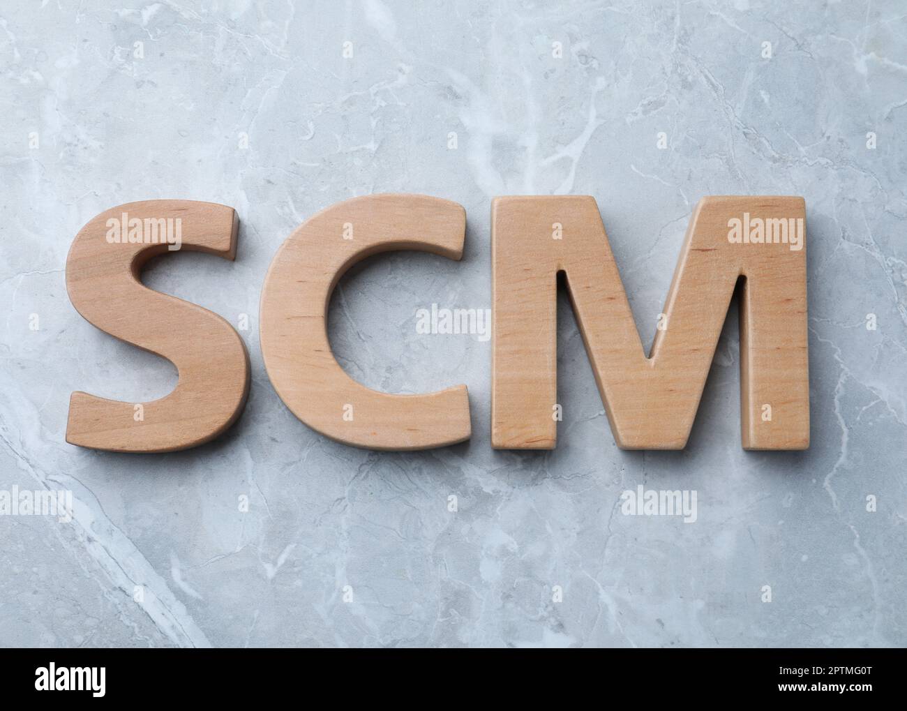 Abbreviation SCM (Supply Chain Management) made of wooden letters on light grey marble background, flat lay Stock Photo