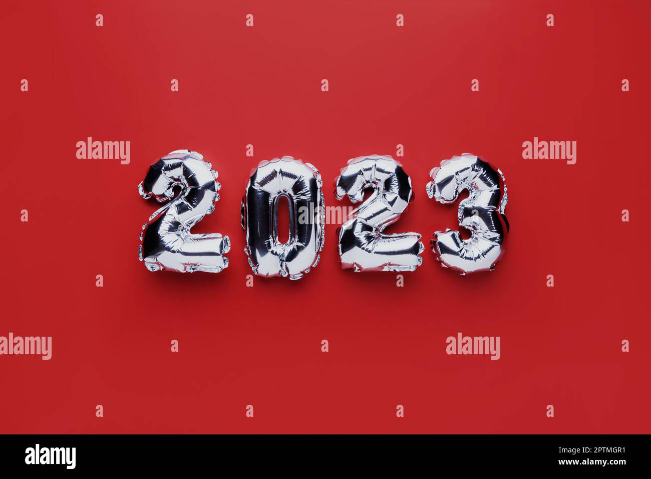 Christmas or New Year background. Red color flat lay with silver shiny 2023 balloon numbers in the center. Simple minimalistic greeting card. Stock Photo