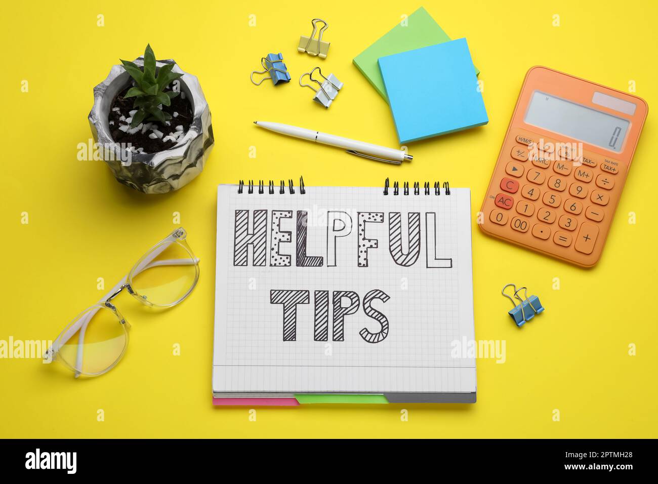 Helpful Tips. Flat lay composition with notebook and calculator on yellow background Stock Photo