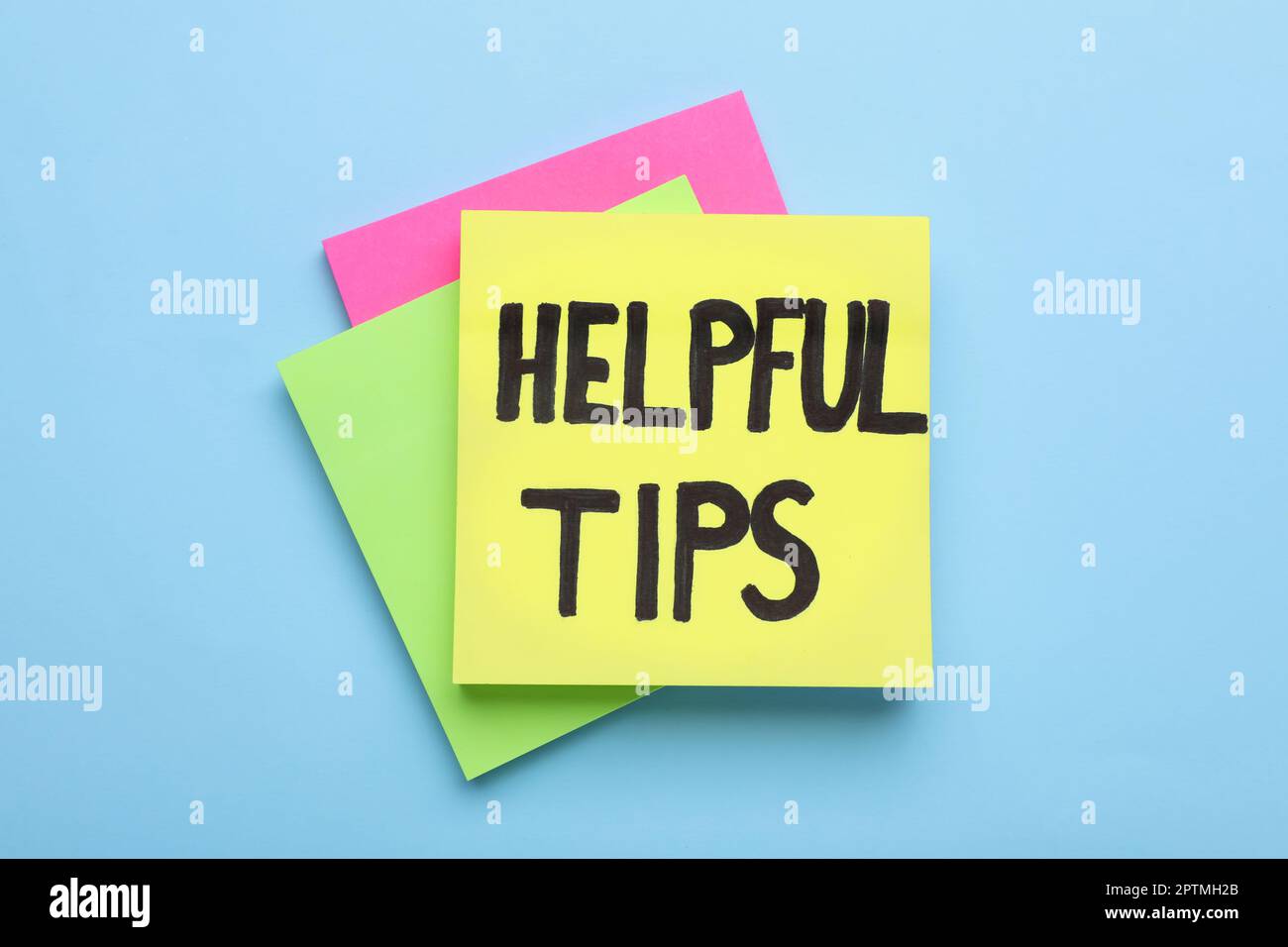 Paper note with phrase Helpful Tips on light blue background, top view Stock Photo