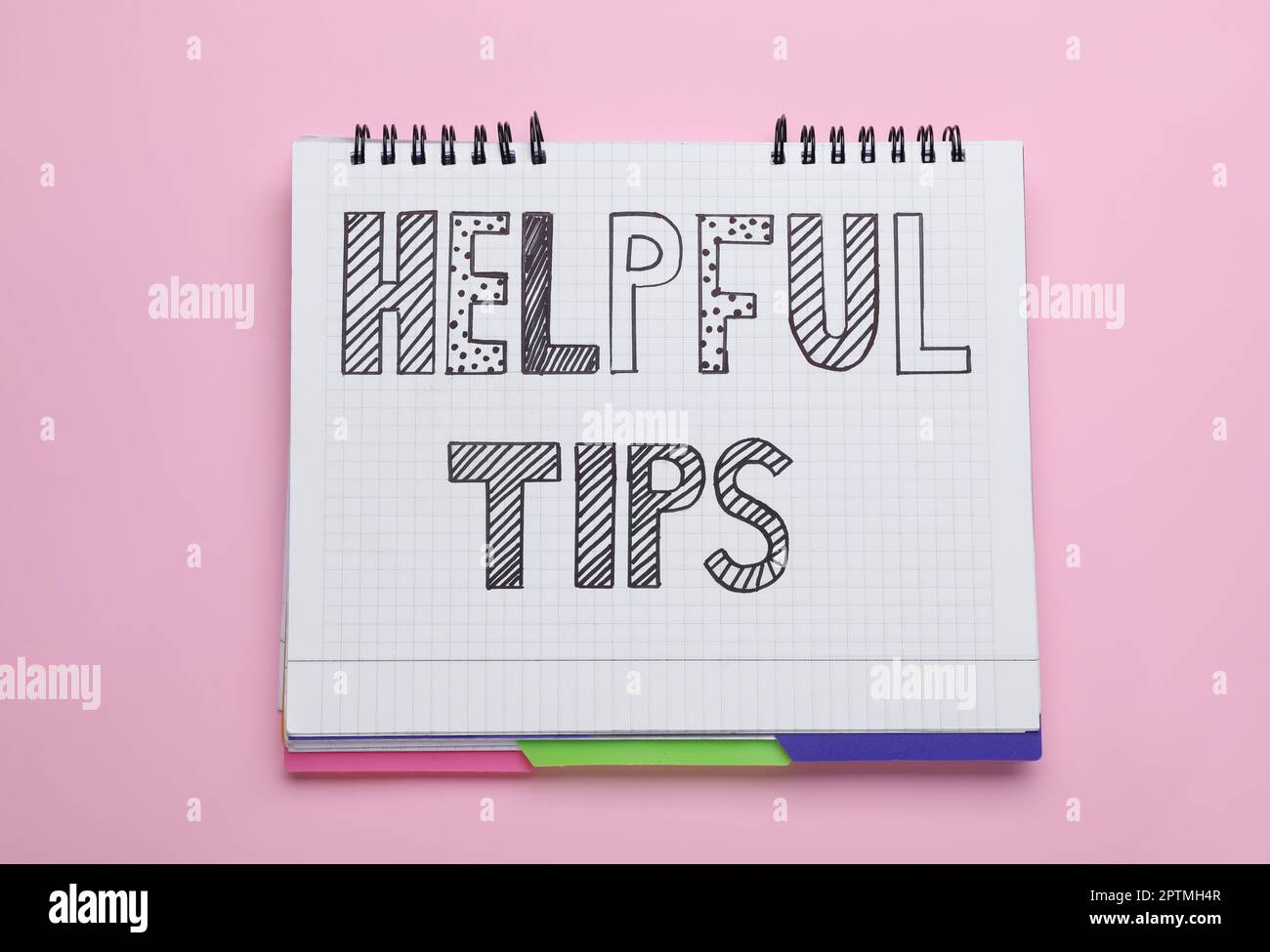 Phrase Helpful Tips in notebook on pink background, top view Stock Photo