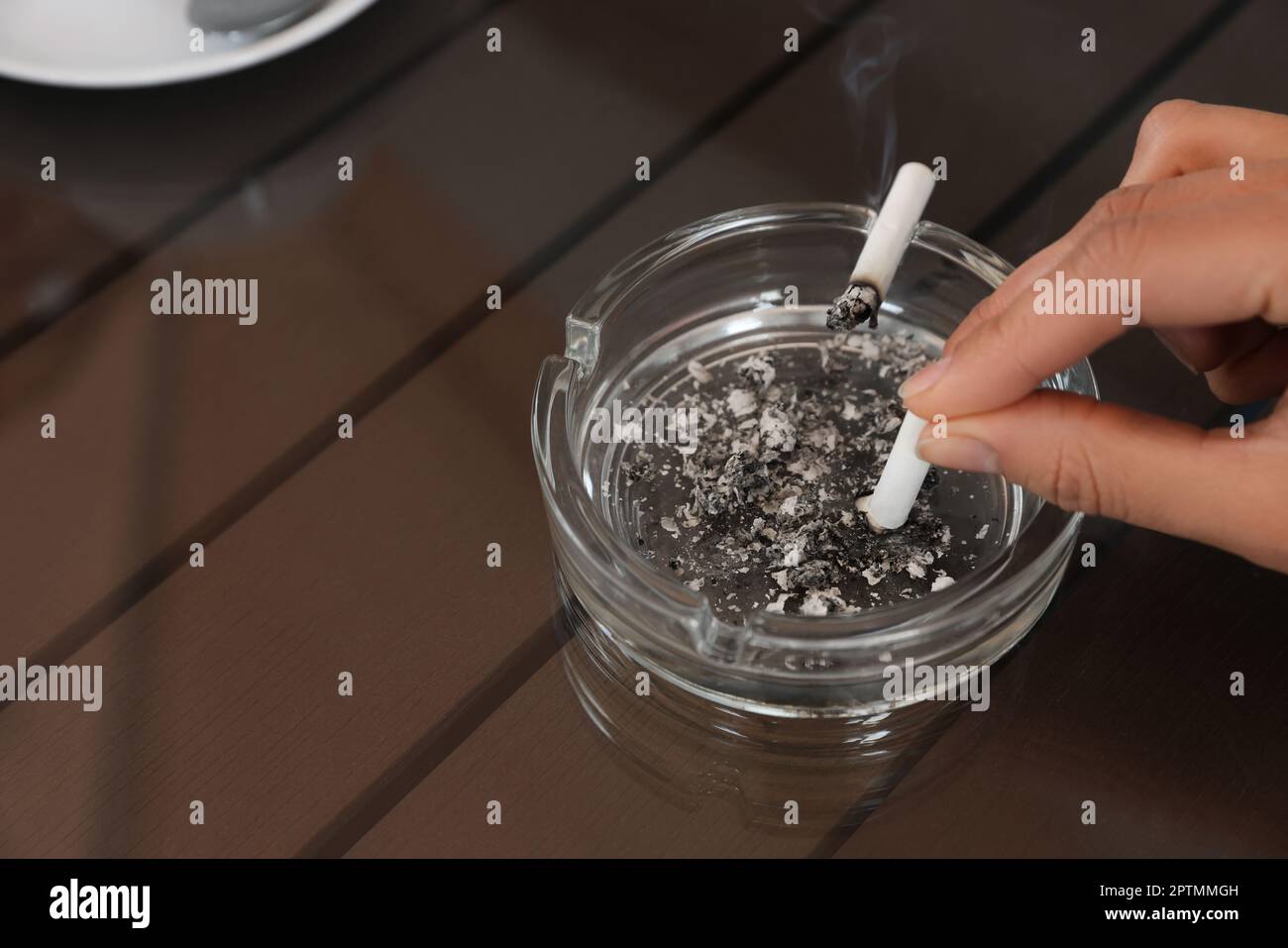 Woman putting out cigarette in ashtray at table, closeup Stock Photo