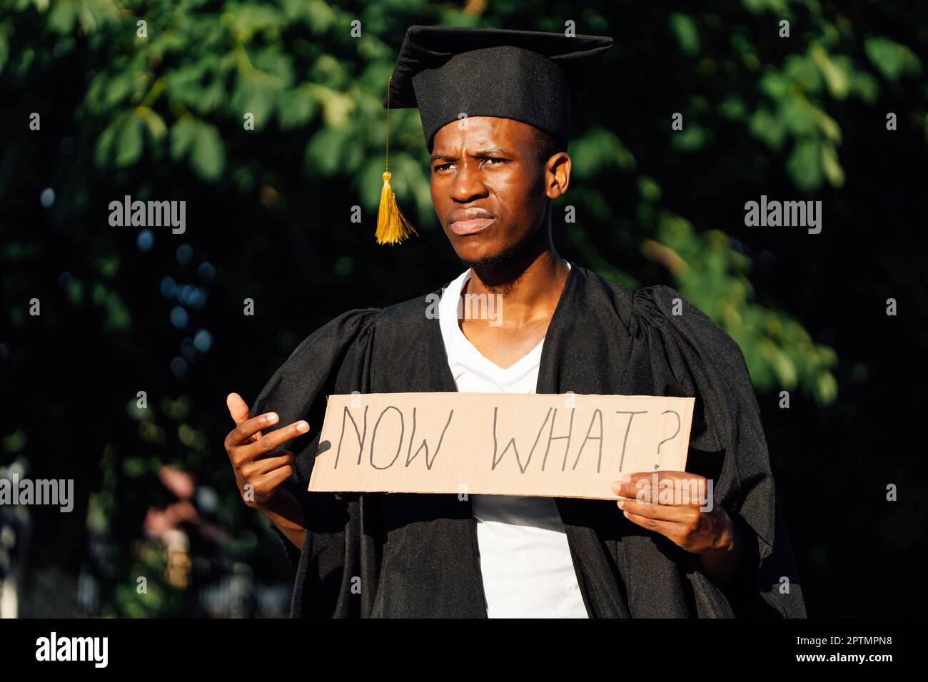 Portrait of discontented afro american guy holding and pointed at cardboard poster on street. Looking for job, hiring and employment issue. University Stock Photo