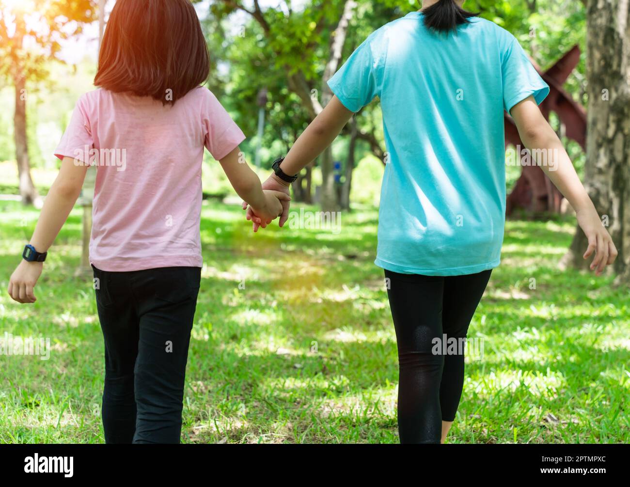 Two sister holding hands in the park in warm spring day. Happy friendship family concept. Stock Photo