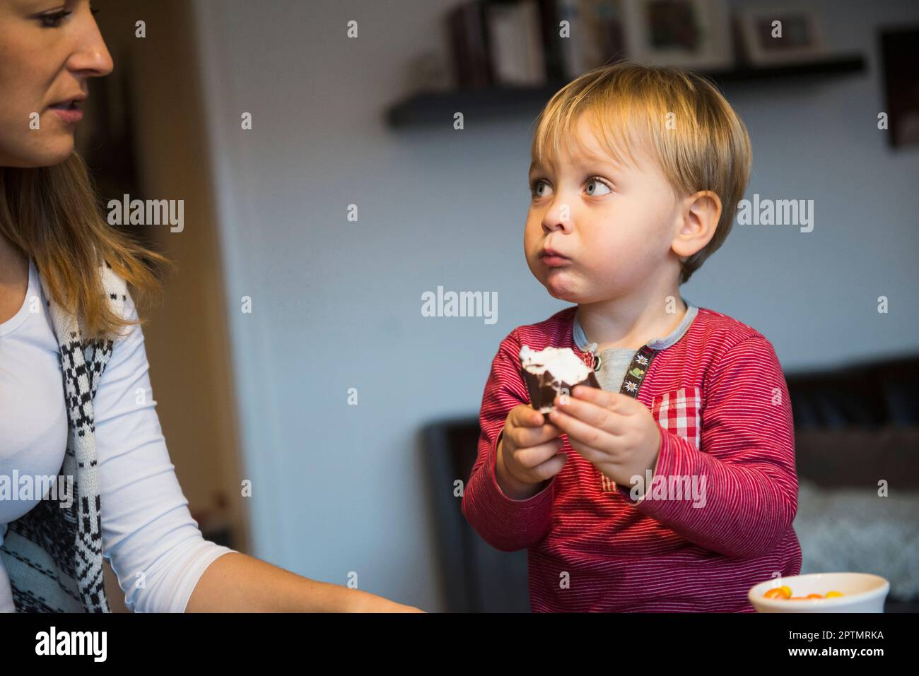 Little boy looking at his mother while eating pastry, Munich, Germany Stock Photo