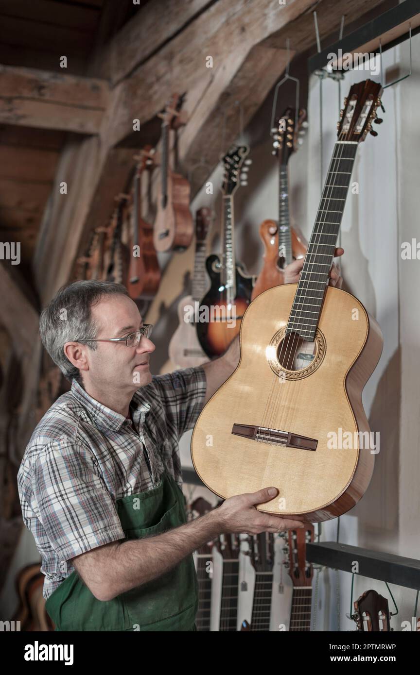 Craftsman picking up guitar at music store Stock Photo