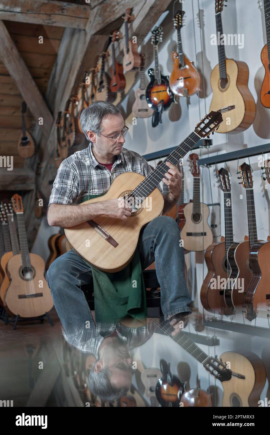 Guitar maker playing guitar in music store Stock Photo Alamy