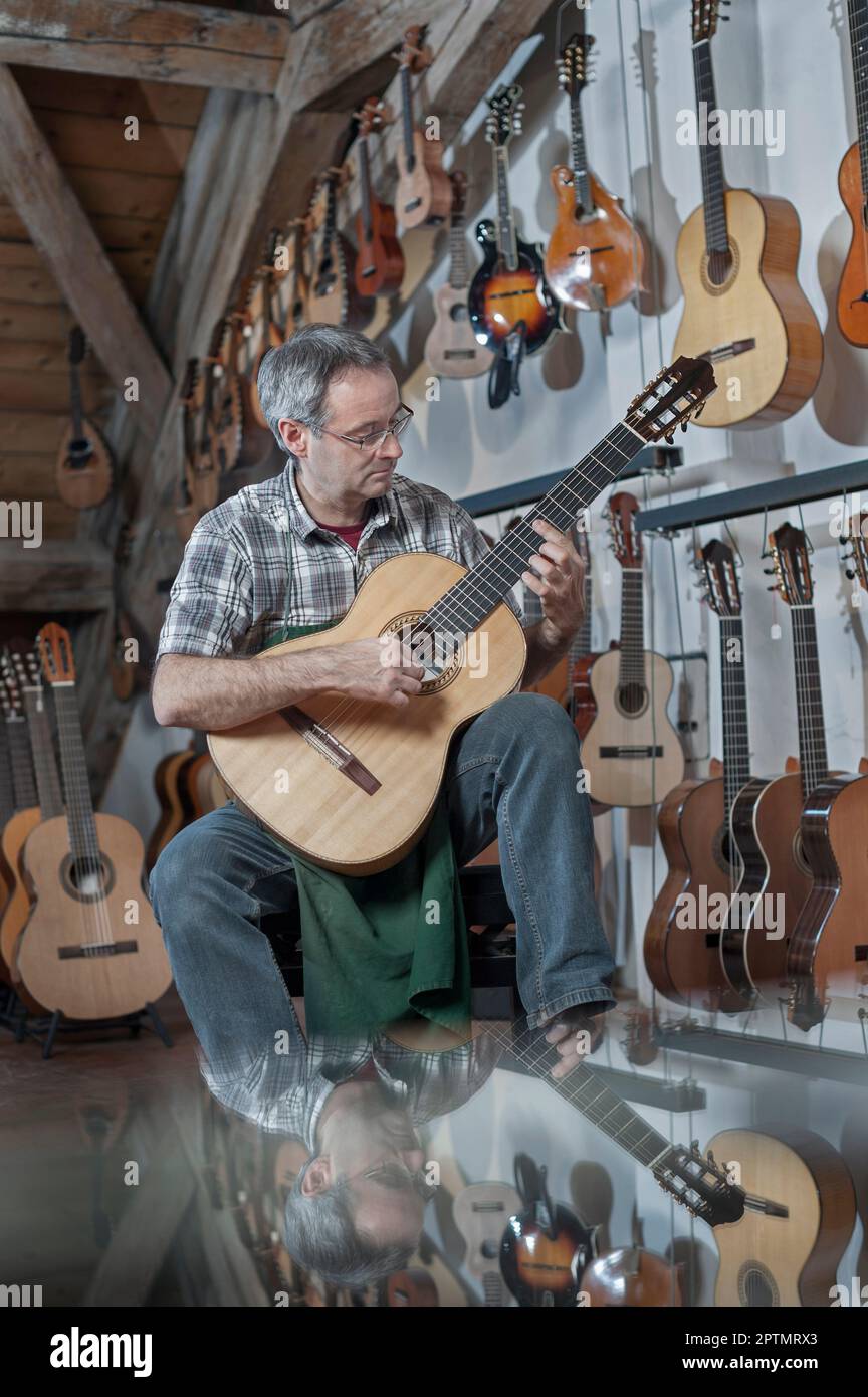 Guitar maker playing guitar in music store Stock Photo