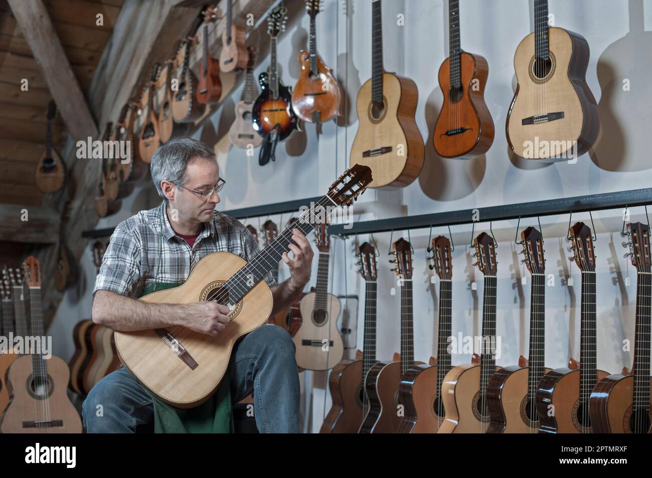 Guitar maker tuning guitar in music store Stock Photo