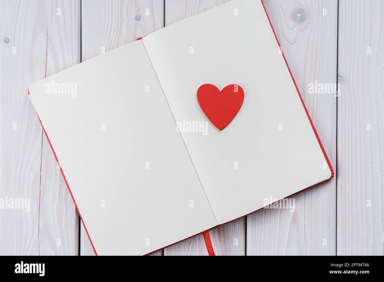 Red diary notebook with white papers, craft red paper heart on page