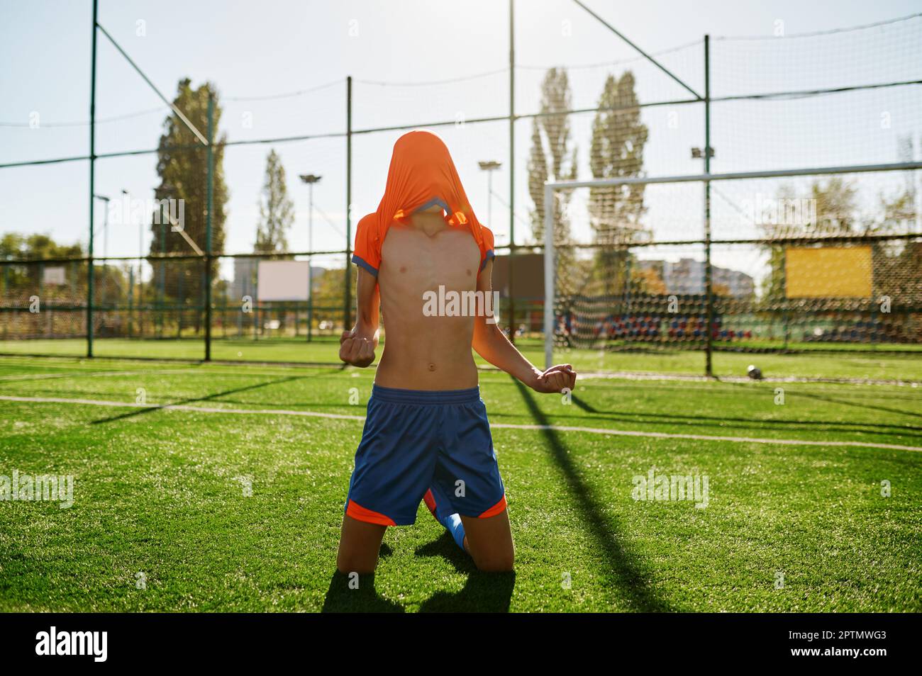 Emotional boy soccer player with tshirt on head rejoicing goal or win
