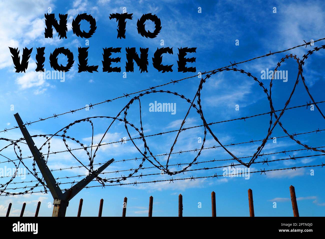 Barbed wire against the blue sky. The inscription in black stop violence. No to violence. The concept of freedom, human rights, imprisonment, restrict Stock Photo