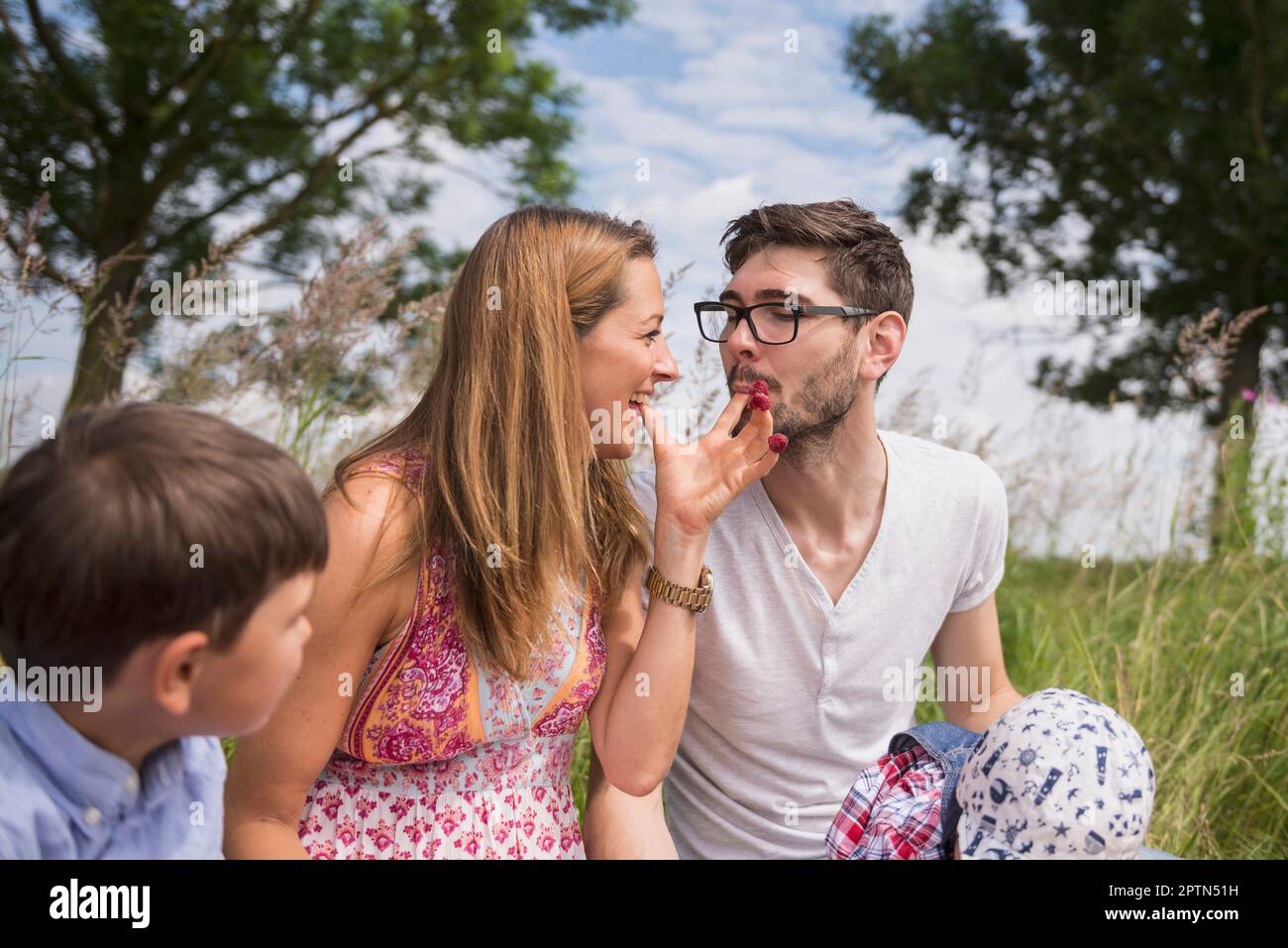 Couple eating raspberries from fingers on meadow in the countryside, Bavaria, Germany Stock Photo