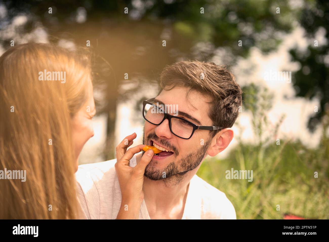 Woman feeding piece of a peach to her husband in the countryside, Bavaria, Germany Stock Photo