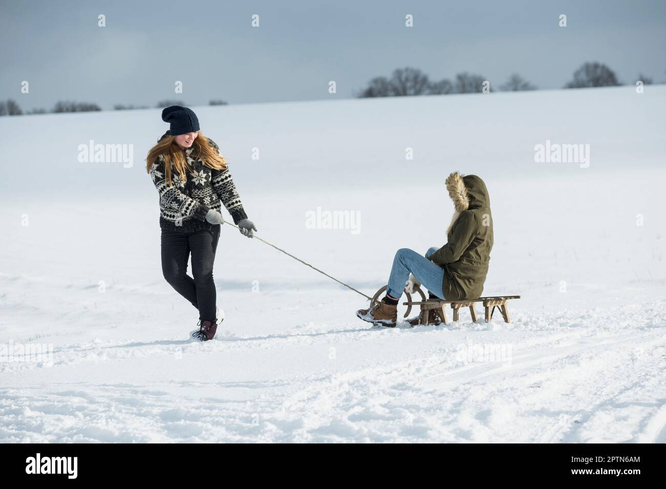 Teenage girl pulling sled in snowy landscape in winter, Bavaria