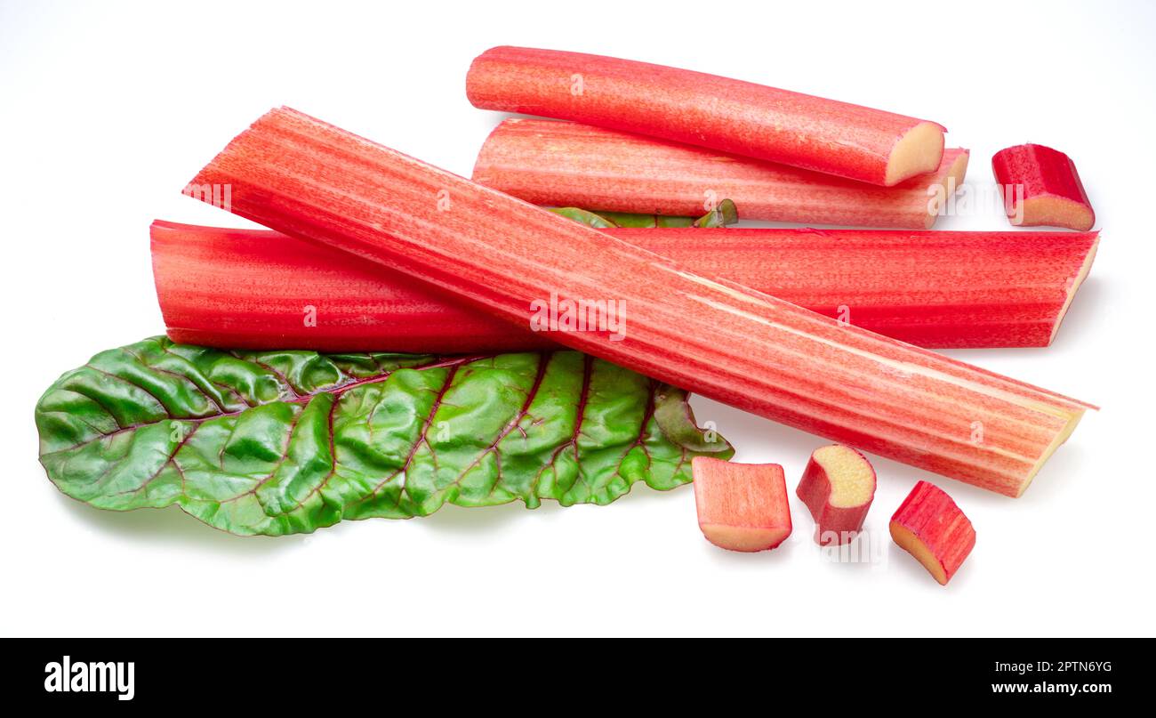 Red rhubarb stems' cuts over rhubarb leaves isolated on white background. Stock Photo