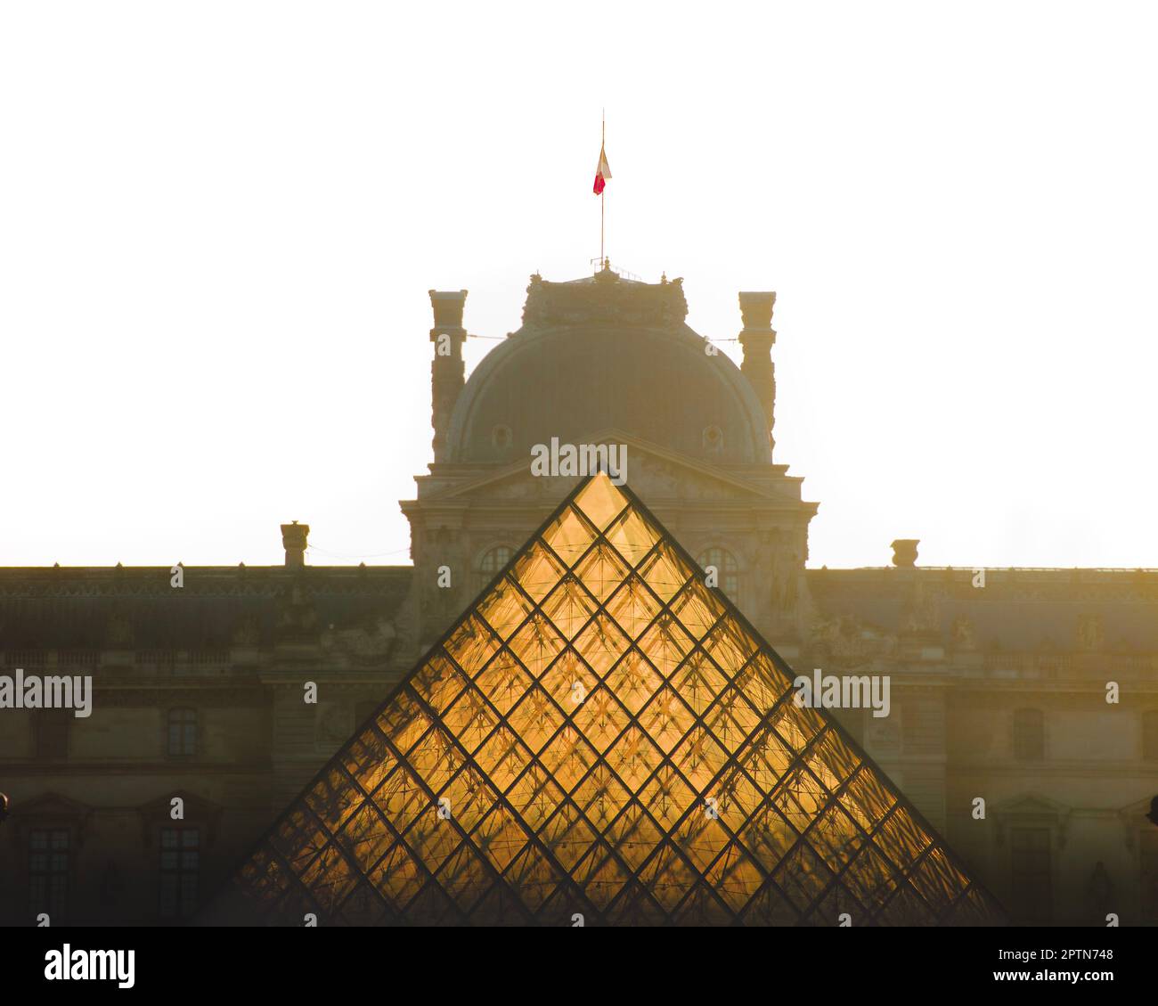 Louvre museum pyramid illuminated by sun rays at sunrise Stock Photo ...
