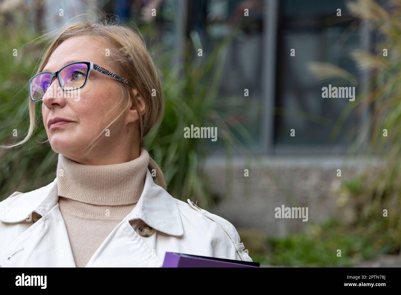 Beautiful matur woman stands near glass building with a folder Stock Photo