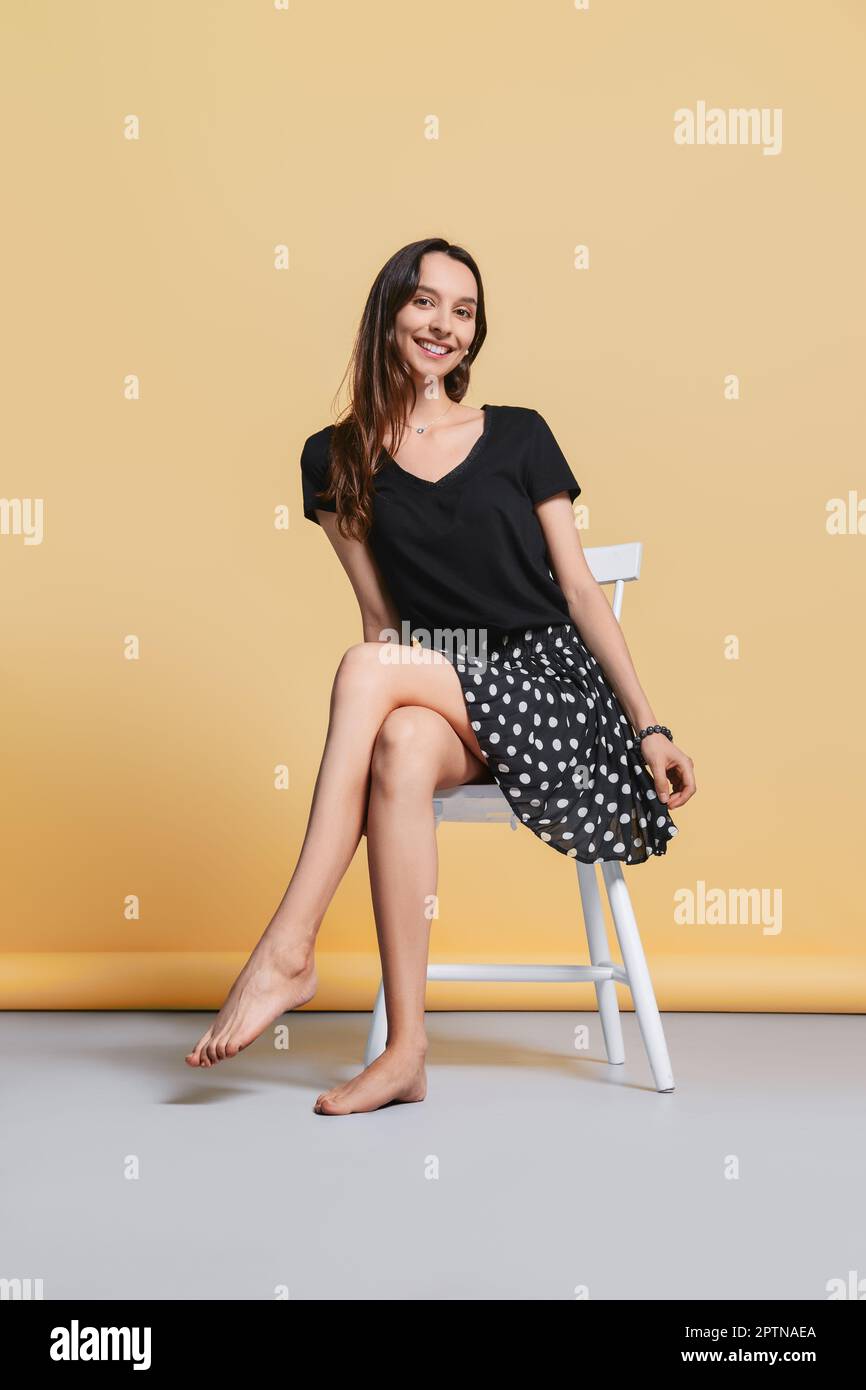 https://c8.alamy.com/comp/2PTNAEA/beautiful-happy-young-woman-without-make-up-sits-on-chair-in-studio-on-yellow-background-2PTNAEA.jpg