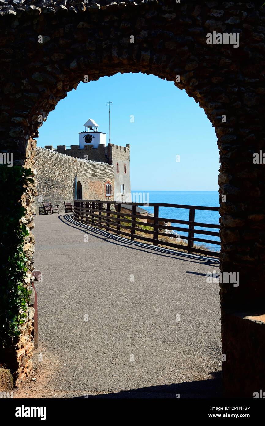 View of the castle overlooking the sea on the edge of Jacobs Ladder beach seen through an arch at Connaught Gardens, Sidmouth, Devon, UK, Europe. Stock Photo