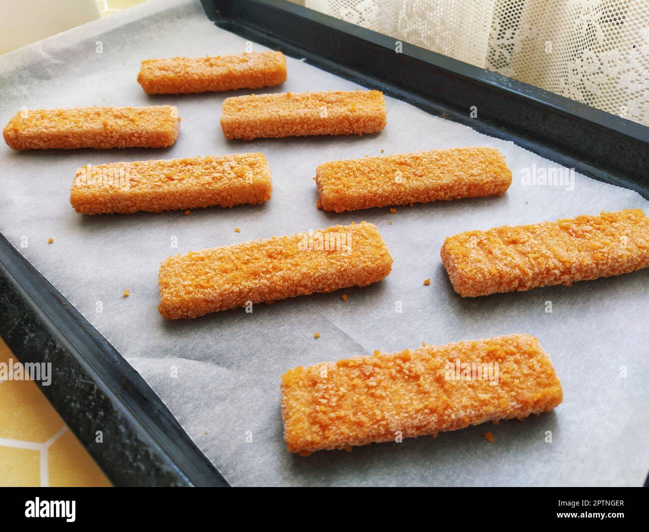 Frozen fish sticks are laid out on baking paper. Cooking a fish delicacy.  Baking paper on a baking sheet. A quick lunch from the oven. Fish menu.  Heal Stock Photo - Alamy