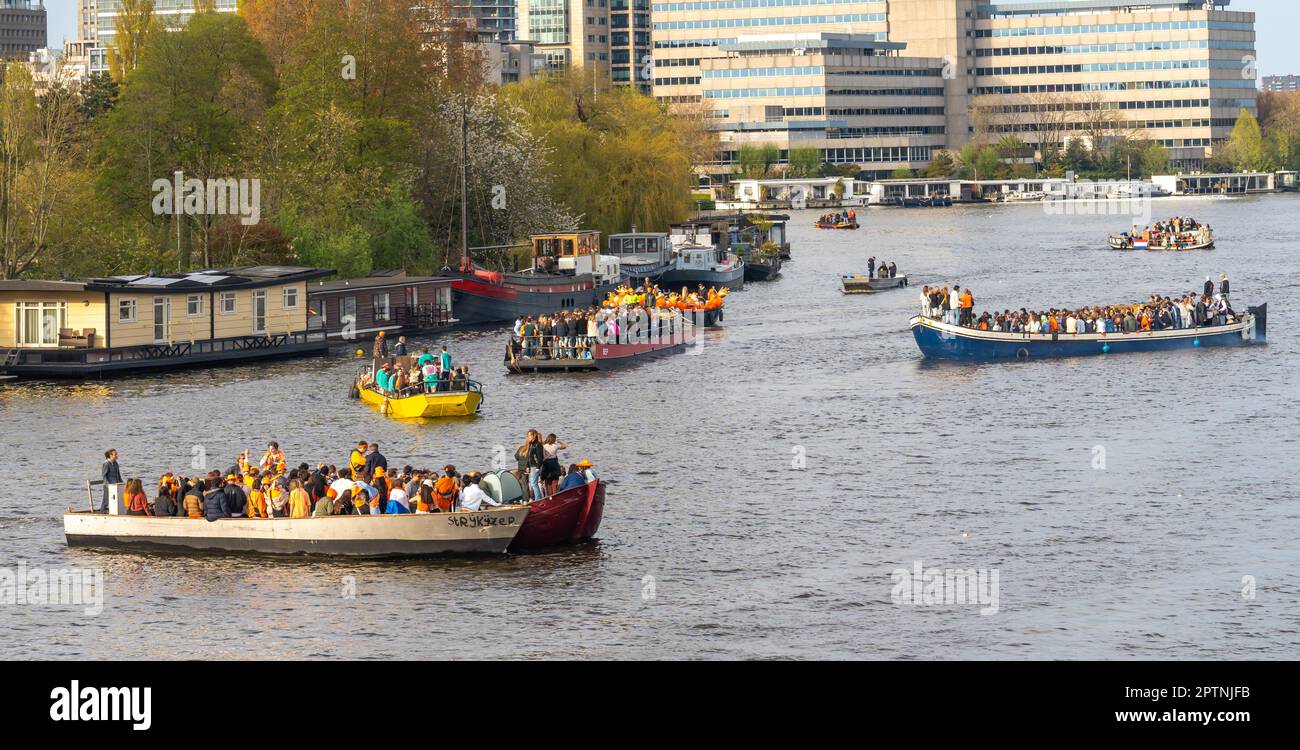 Amsterdam, The Netherlands, 27.04.2023, Party boats on river Amstel with people celebrating King's Day (Koningsdag in dutch) Stock Photo
