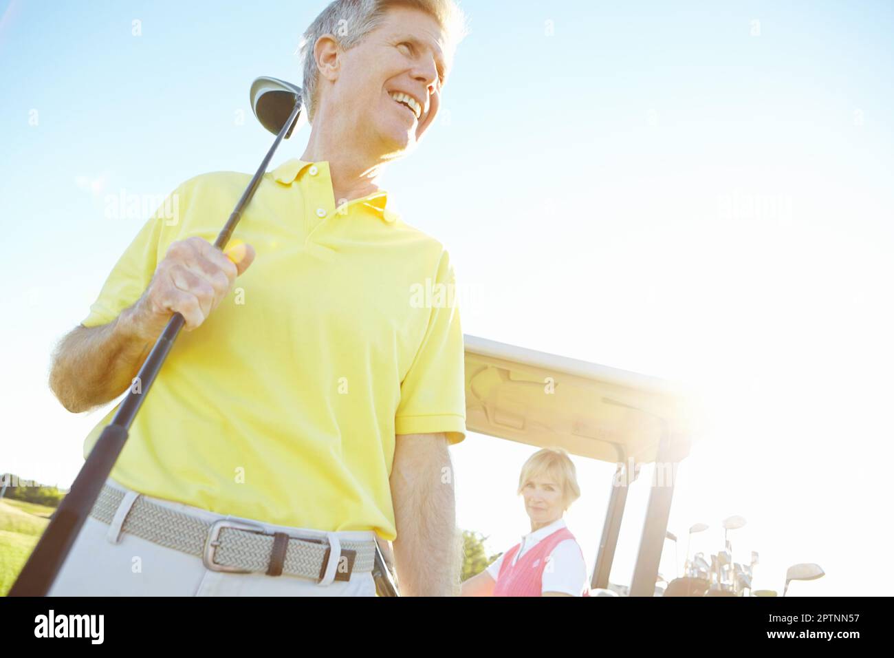 Visions of improving his handicap. Low angle shot of a handsome older golfer standing in front of a golf cart with his golfing buddy behind the wheel. Stock Photo